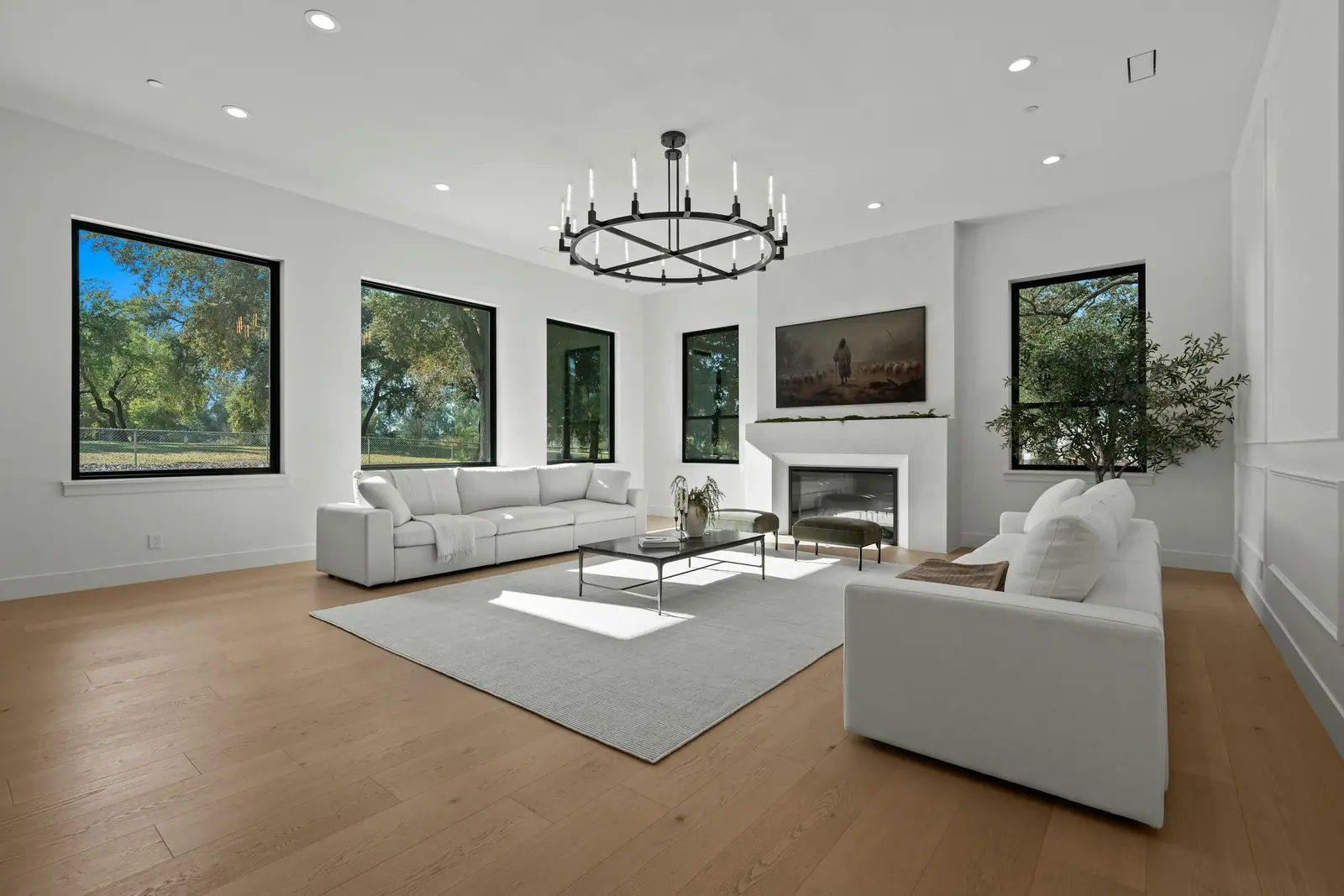Illustrative photo of a bright living room with pale sofas, a fireplace and large windows.