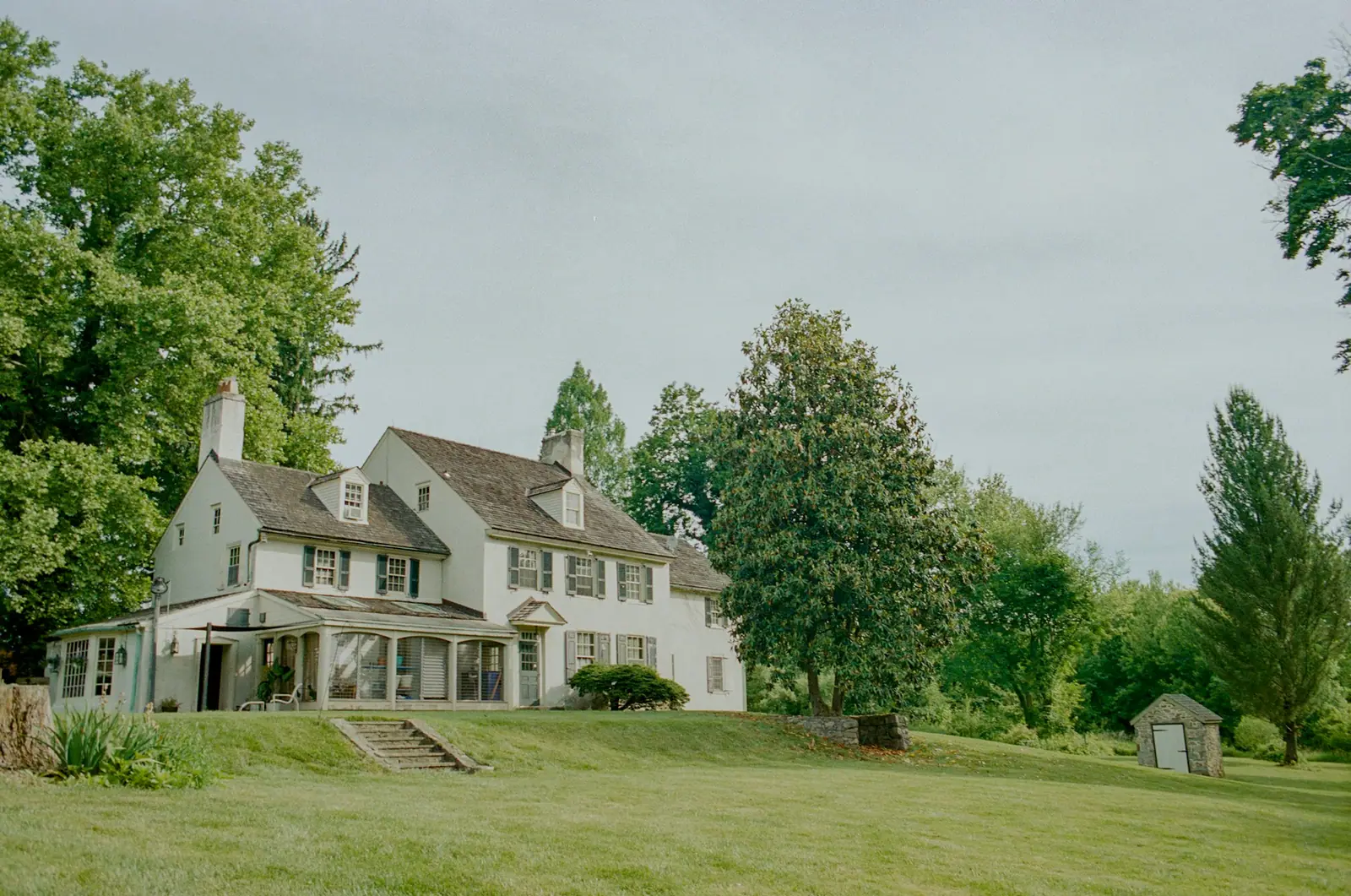 Illustrative photo of a white home with a green lawn and mature trees.